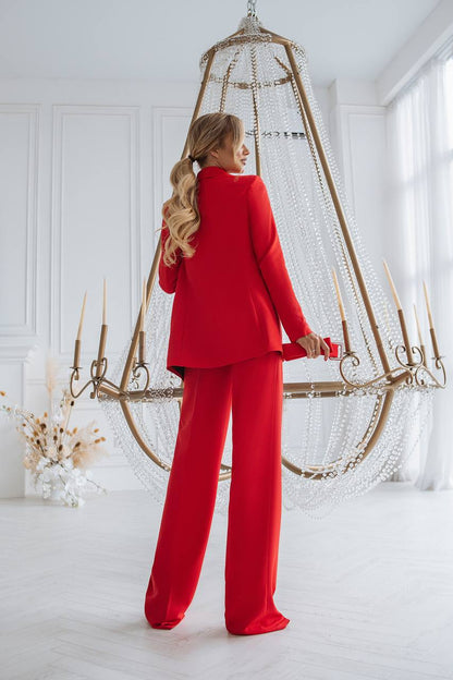 Woman in a red outfit standing in a bright room with a decorative hanging chair.