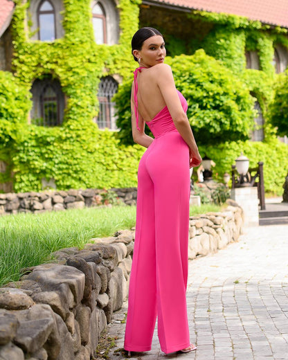 Woman in a pink jumpsuit standing in front of a ivy-covered building.