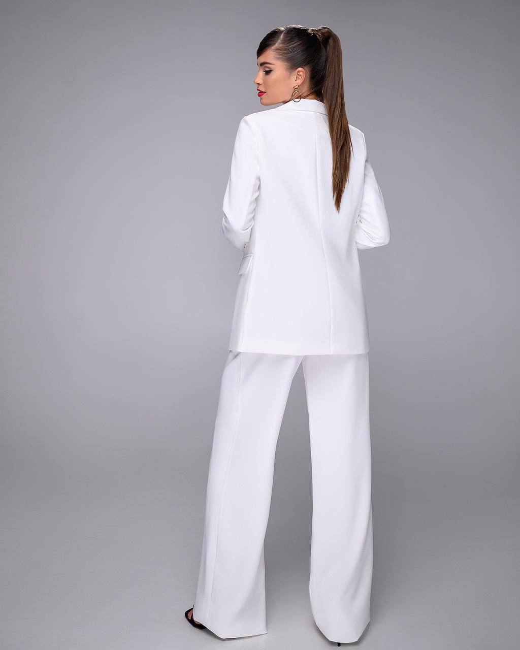 Woman wearing a white suit against a gray background