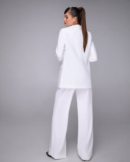 Woman wearing a white suit against a gray background