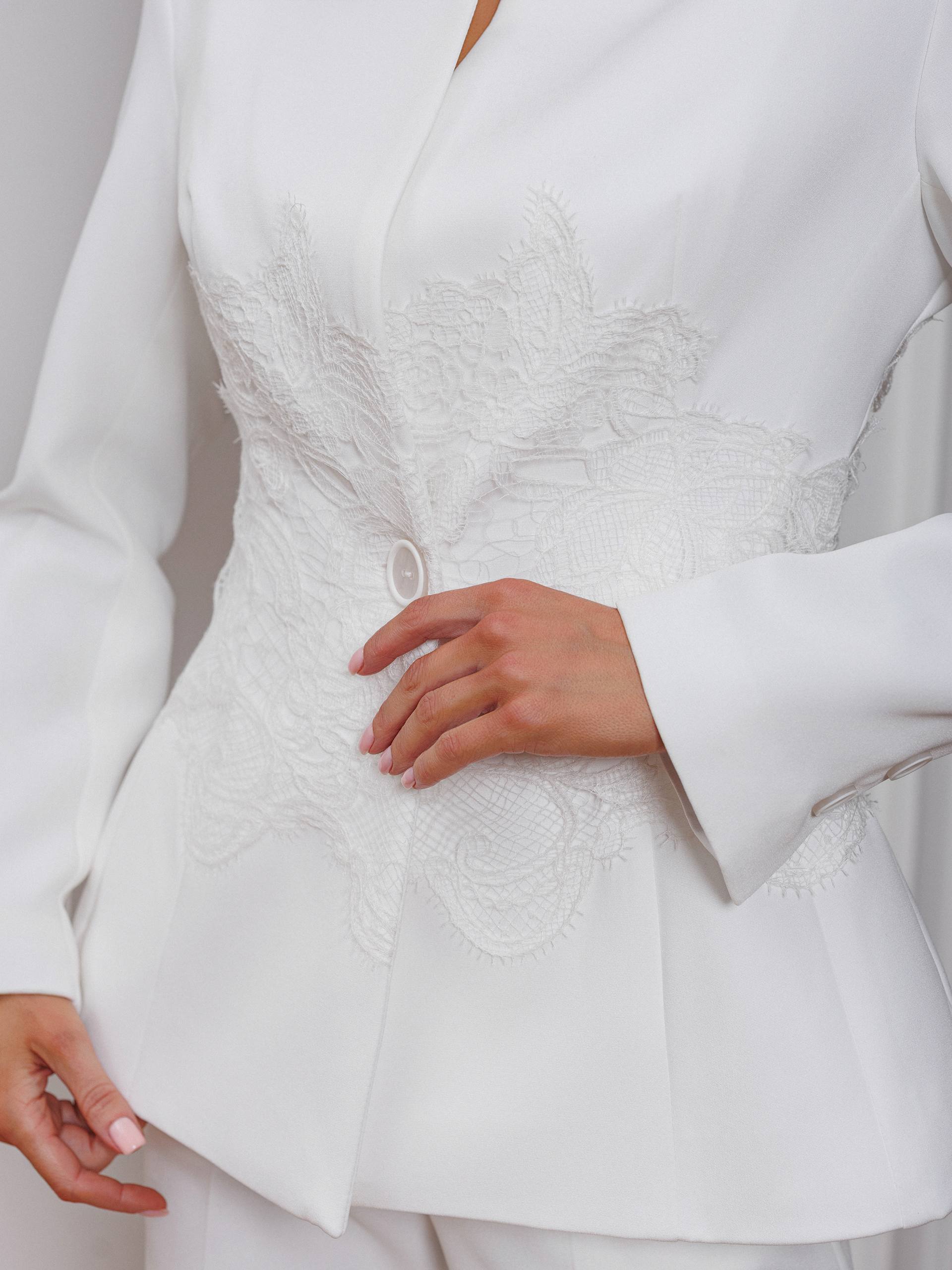 Close-up of a white suit with intricate detailing on the lapel.