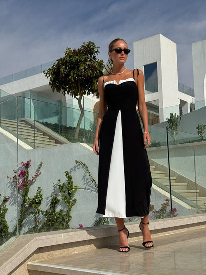 Woman in a black and white dress standing in front of modern architectural buildings.
