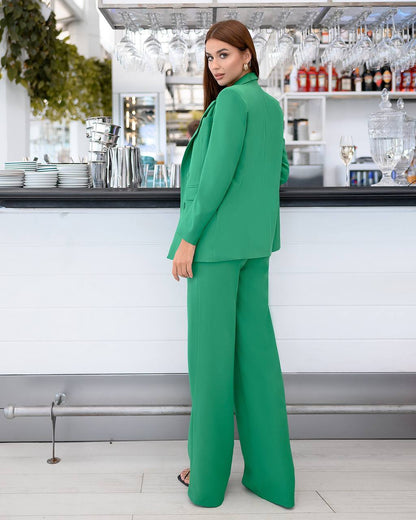 Woman in a green suit standing in a modern kitchen.