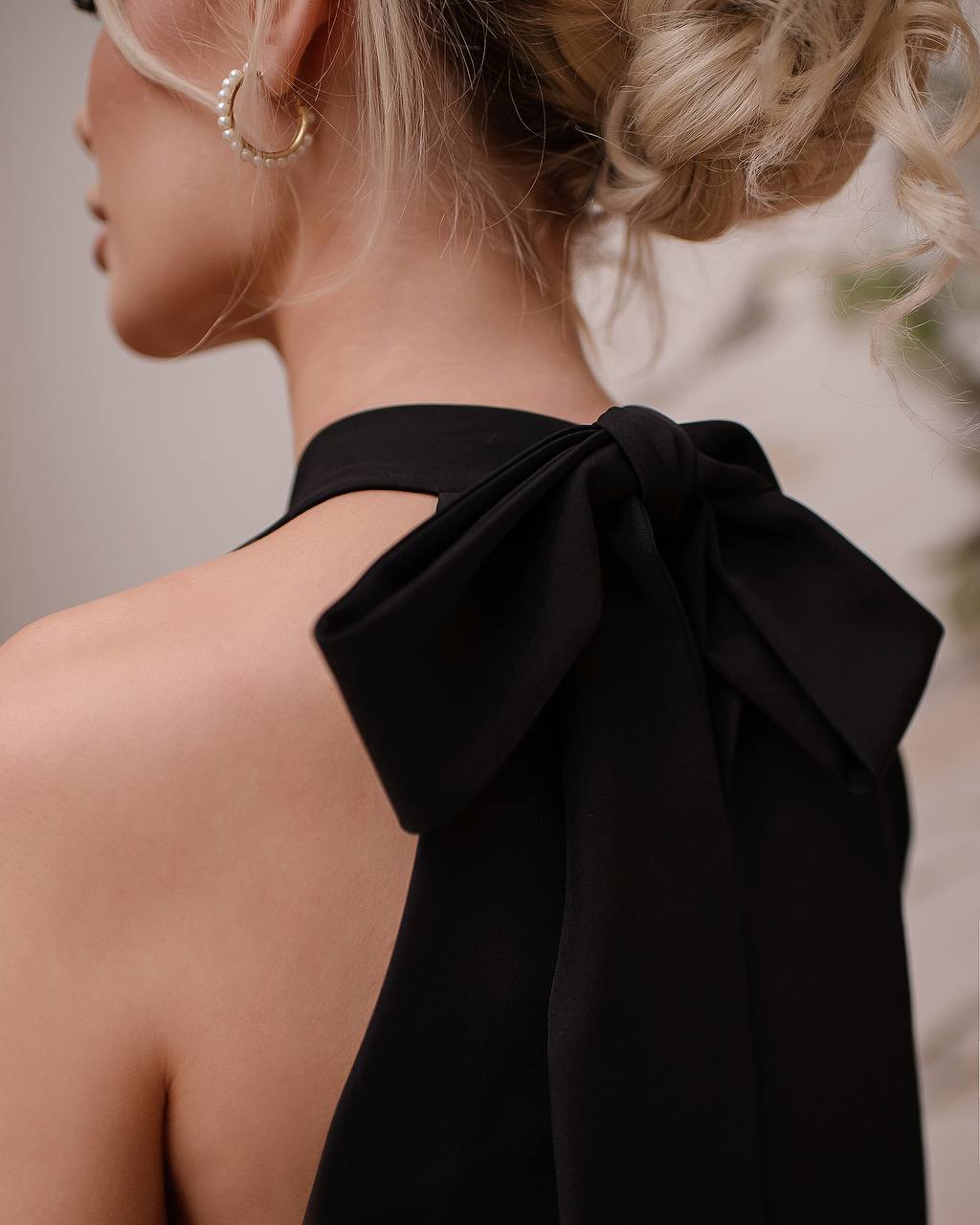 Black halter top with a large bow detail on a blurred background