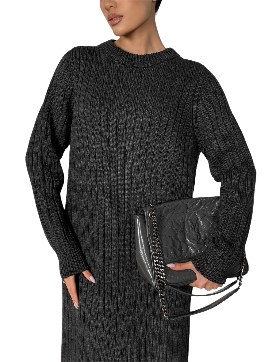 Woman wearing a black ribbed sweater holding a black clutch against a white background