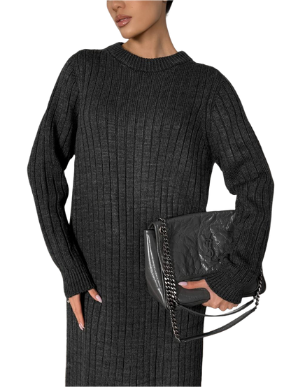 Woman wearing a black ribbed sweater holding a black clutch against a white background
