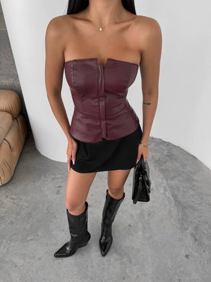 Person wearing a strapless leather top and black skirt with black boots indoors.