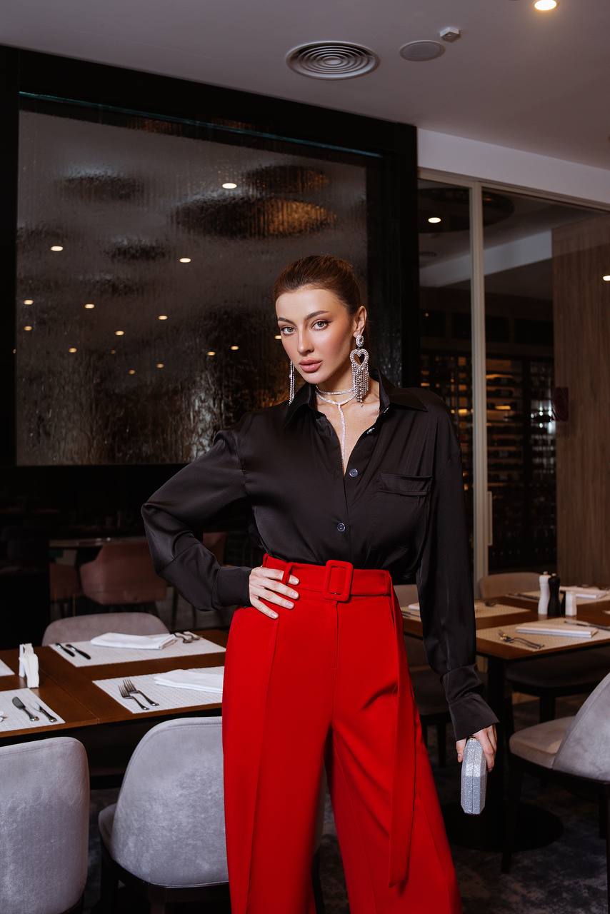 Woman in a black shirt and red pants standing in a restaurant.
