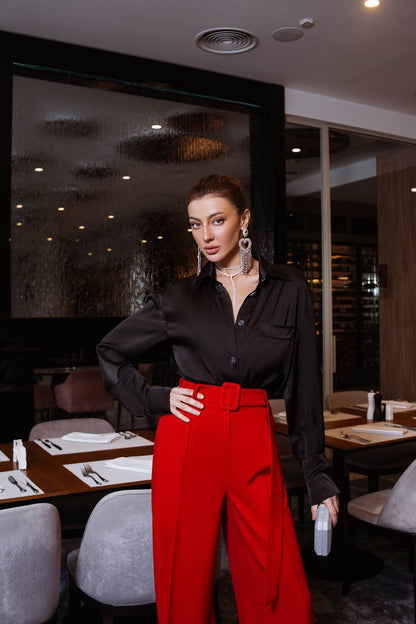 Woman in a black shirt and red pants standing in a restaurant.