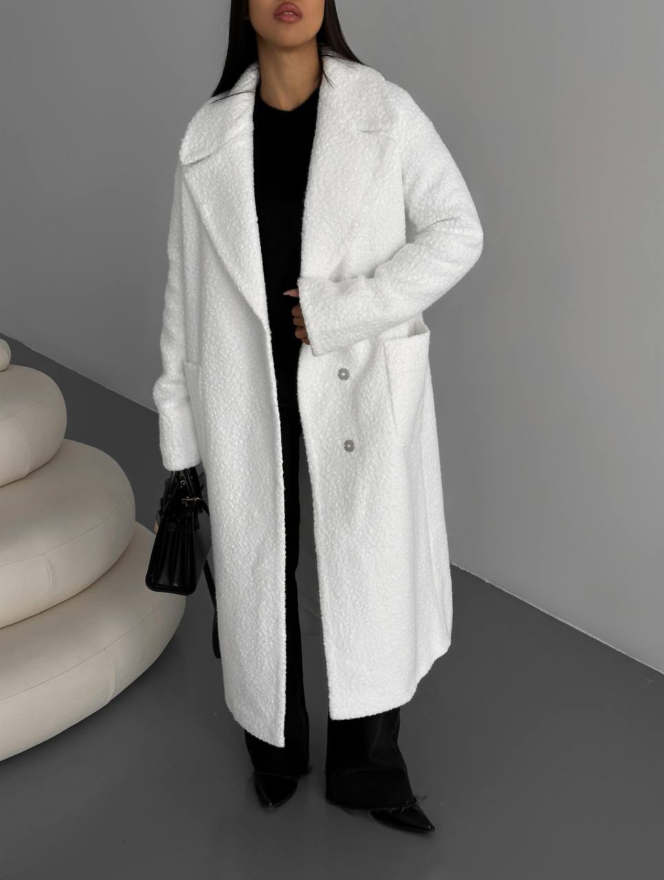 Person wearing a long white coat with a neutral background