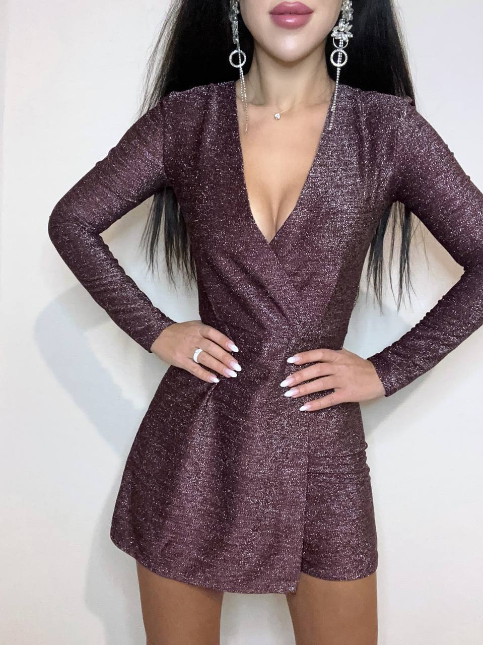 Woman wearing a sparkly purple dress with long sleeves on a white background