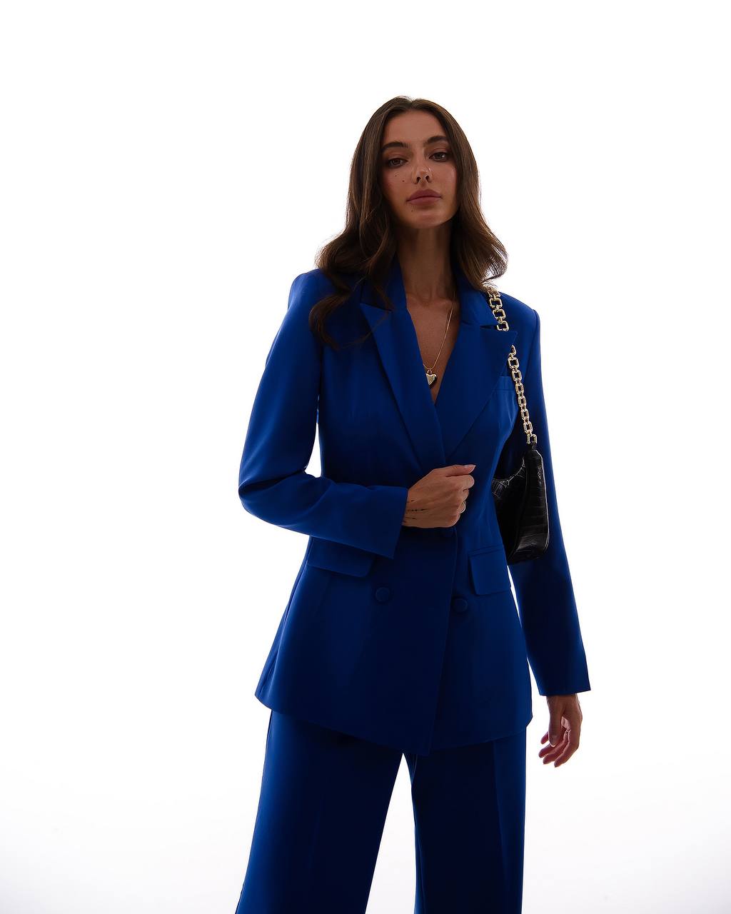 Woman wearing a blue suit with a black handbag on a white background