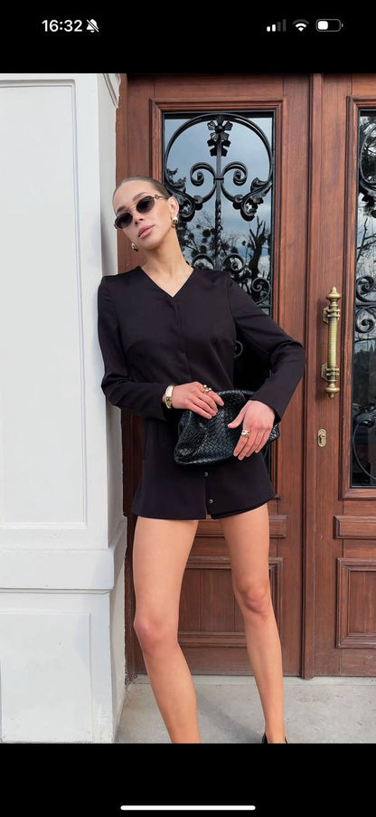 Person wearing a black outfit standing in front of a wooden door with glass panels.