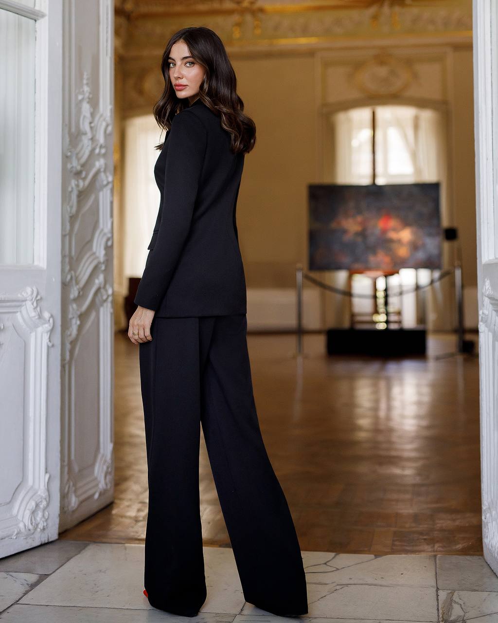 Woman in a black suit standing in an elegant interior setting