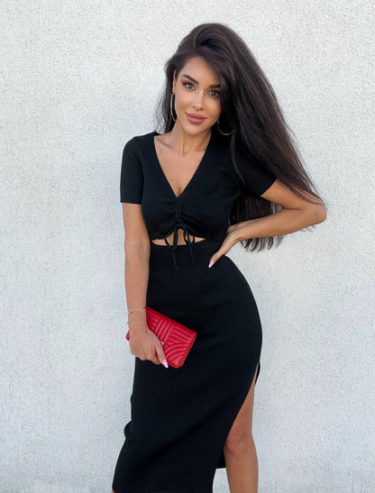 Woman in a black dress holding a red clutch against a light gray background