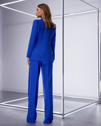 Woman wearing a blue suit standing in front of a reflective surface.