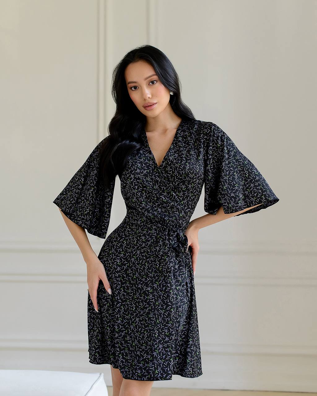 Woman wearing a black floral dress against a neutral background