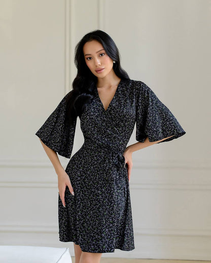 Woman wearing a black floral dress against a neutral background