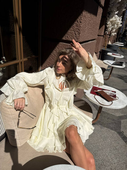 Woman in a white dress sitting on a chair with a table in front of her.