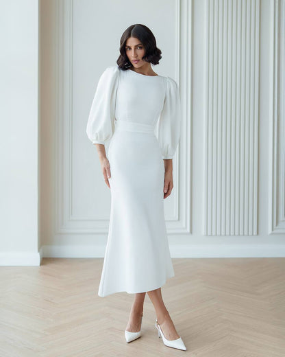 Woman wearing a white dress with puffed sleeves in a minimalistic setting