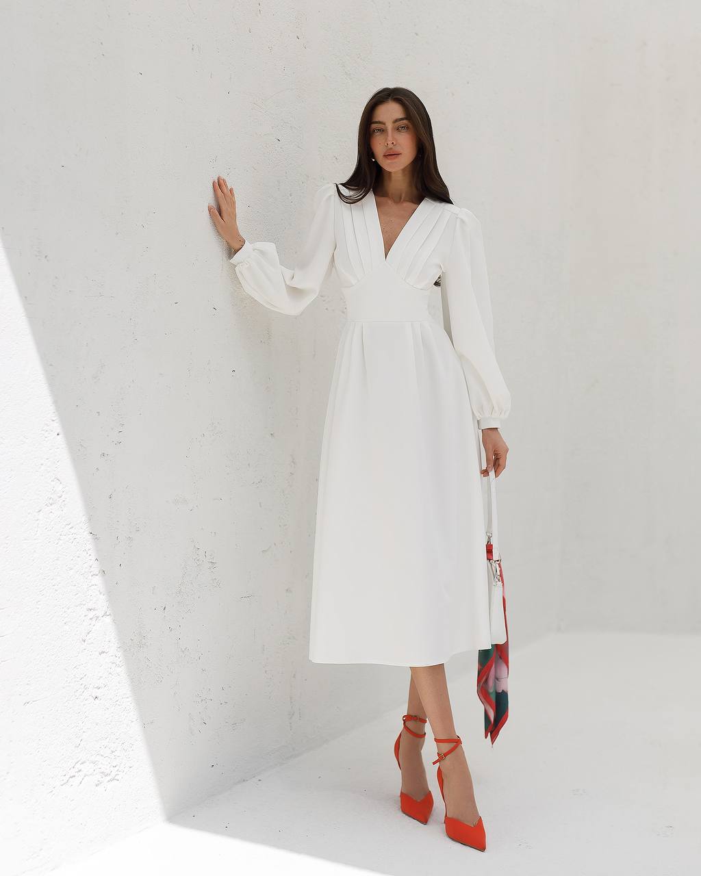 Woman in a white dress with a floral scarf, standing against a white background