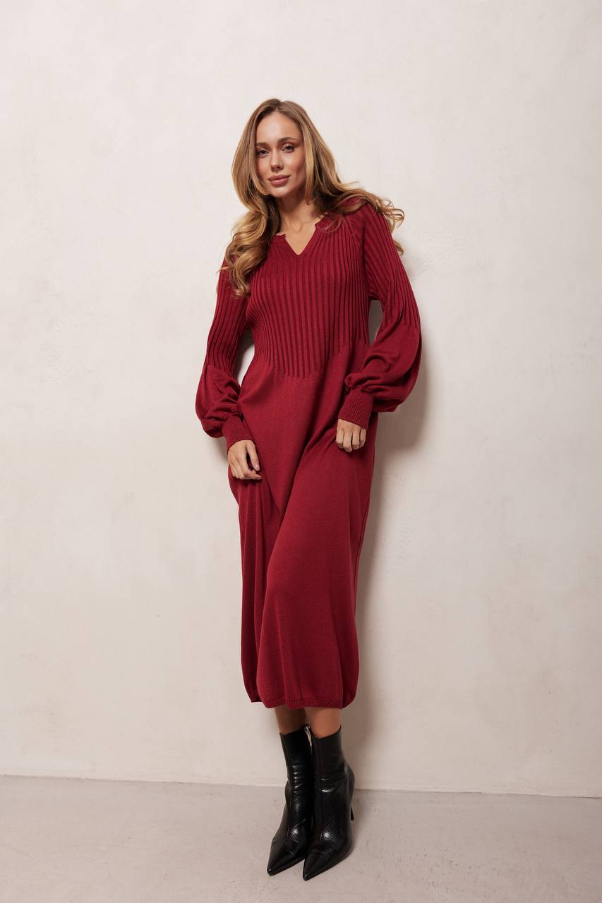 Woman wearing a red ribbed dress with long sleeves against a white background