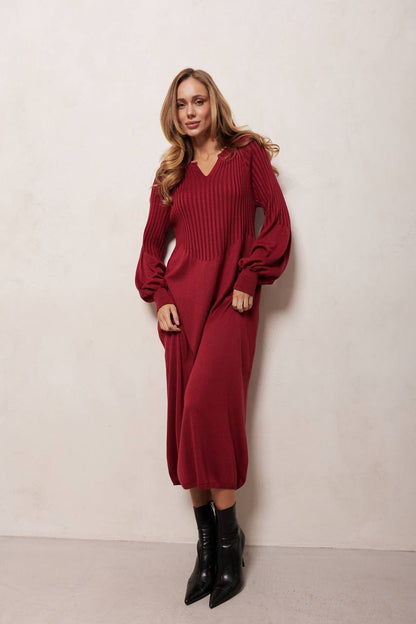 Woman wearing a red ribbed dress with long sleeves against a white background