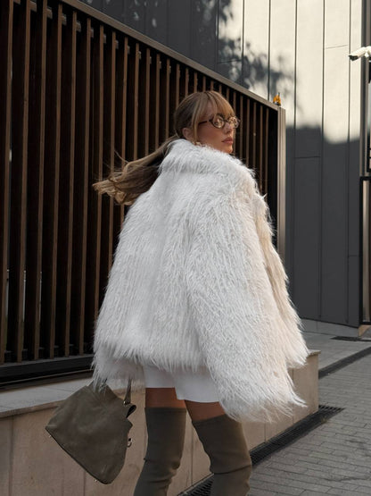 Woman wearing a white fluffy coat walking outdoors.