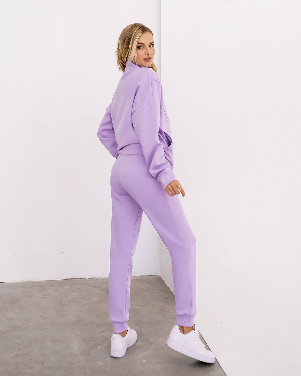 Woman wearing a lavender tracksuit against a white background