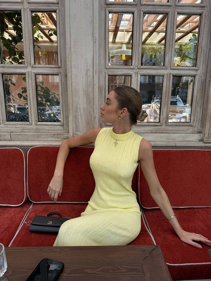 Woman in a yellow dress sitting on a red couch in a cafe.