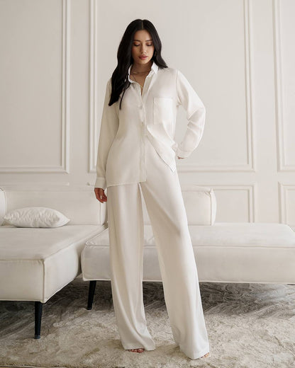 Woman wearing a white pajama set in a room with a white sofa.