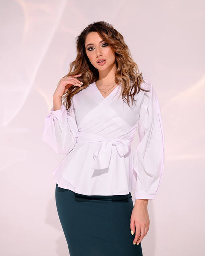 Woman wearing a white blouse with long sleeves and a green skirt on a light pink background