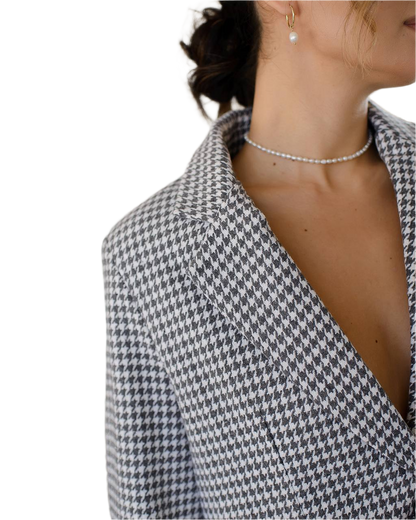 Houndstooth patterned blazer worn by a person on a white background