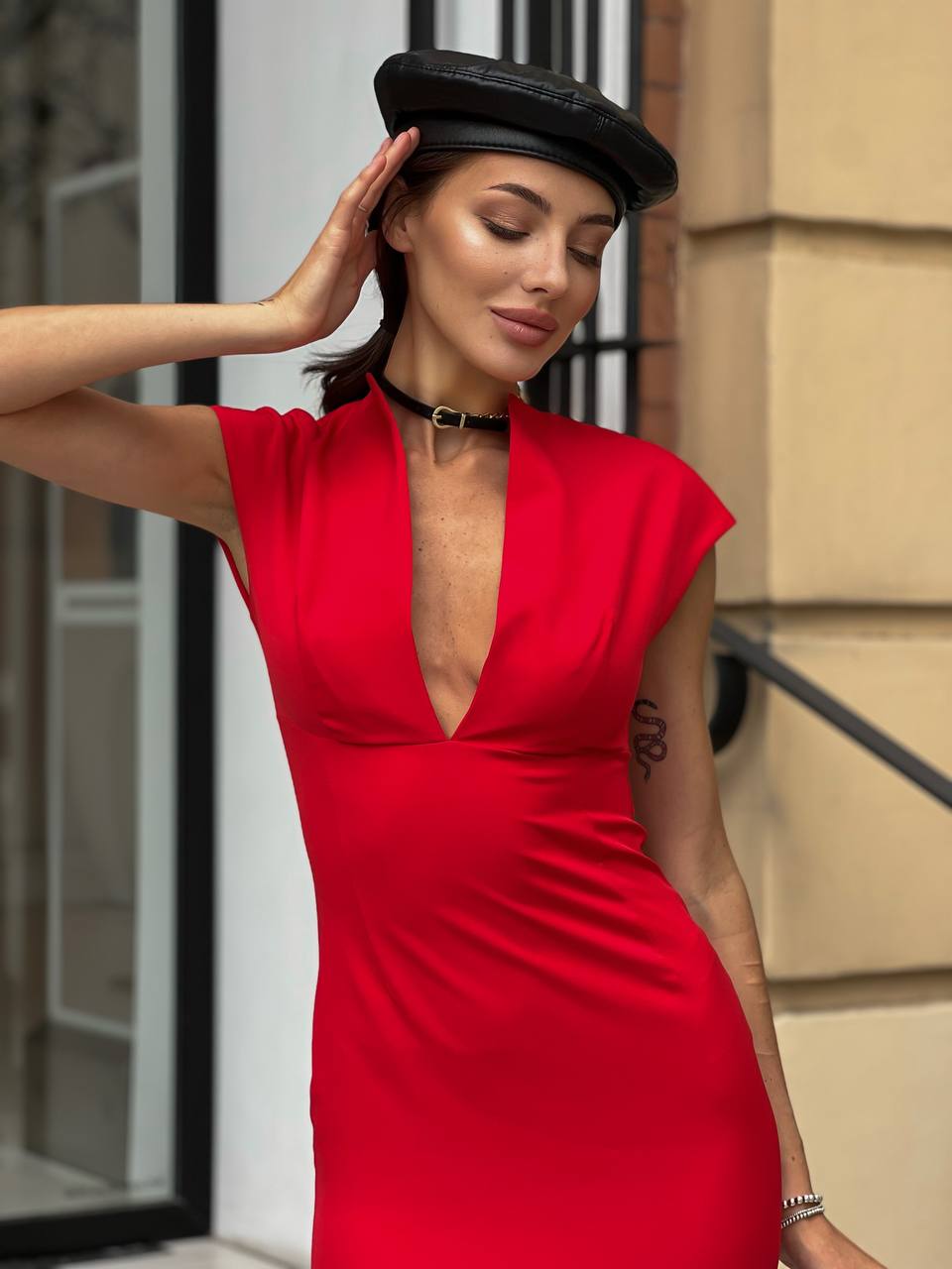 Woman wearing a red dress and black beret standing outdoors.