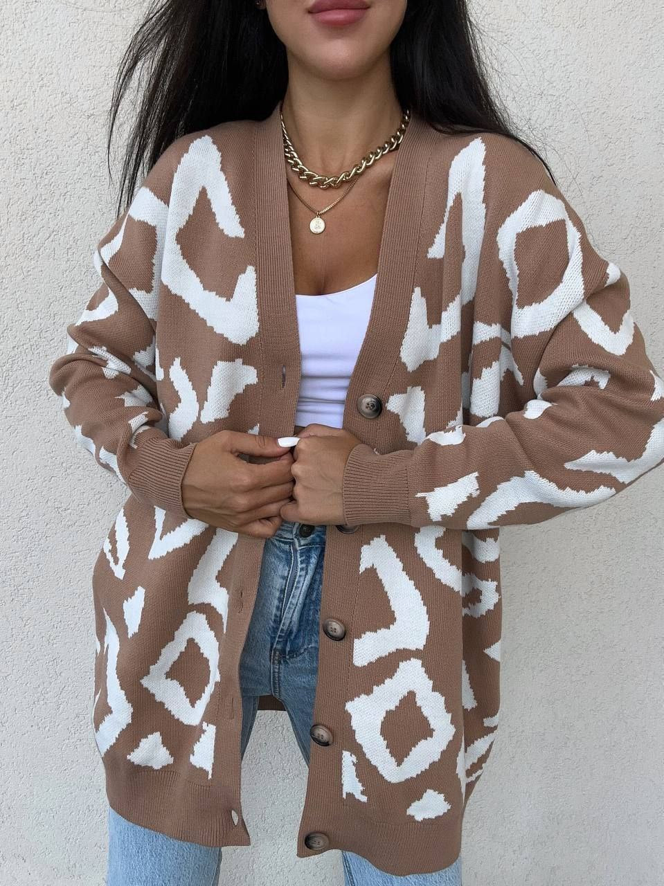 Person wearing a brown cardigan with white pattern against a plain background