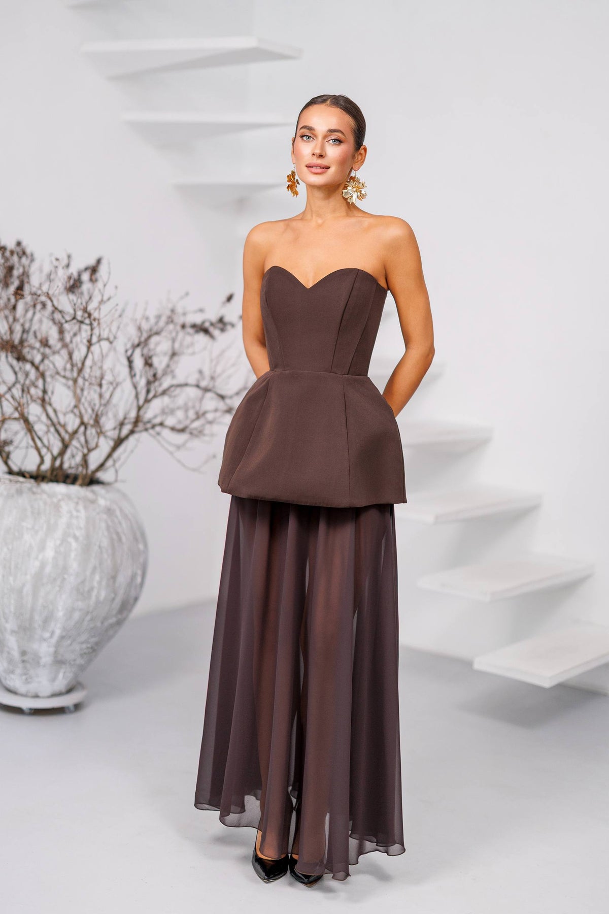 Woman wearing a strapless brown evening gown against a white background