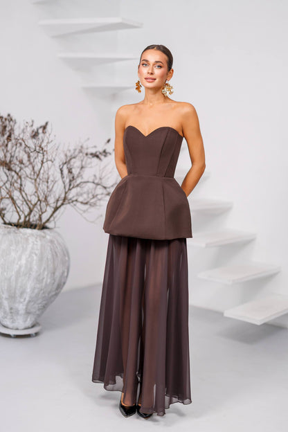 Woman wearing a strapless brown evening gown against a white background