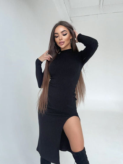 Woman wearing a black dress with a slit, standing against a white background