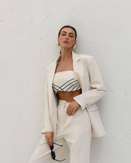 Woman wearing a white outfit with a black and white patterned top against a white background