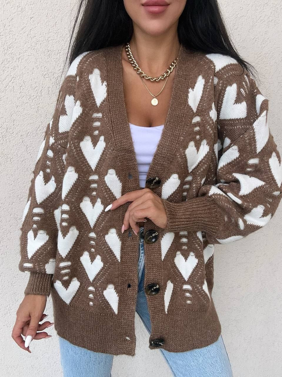 Person wearing a brown cardigan with white pattern against a plain background