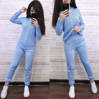 Woman wearing a light blue cable knit sweater and pants, standing in front of a mirror.