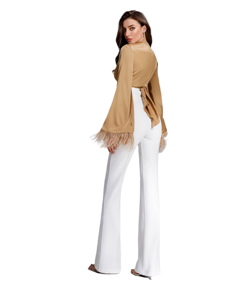 Woman wearing a beige cardigan with fringe and white pants on a white background