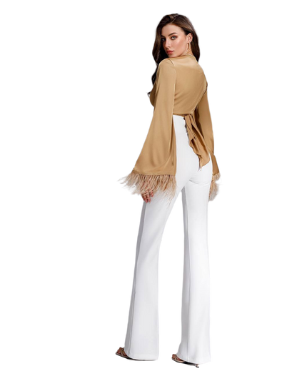 Woman wearing a beige cardigan with fringe and white pants on a white background