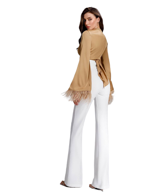 Woman wearing a beige cardigan with fringe and white pants on a white background