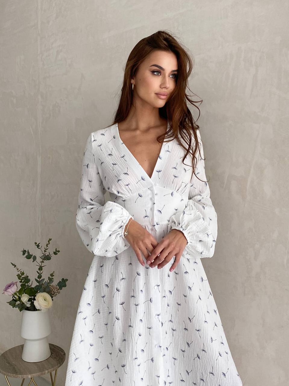 Woman wearing a white dress with a subtle pattern against a plain background