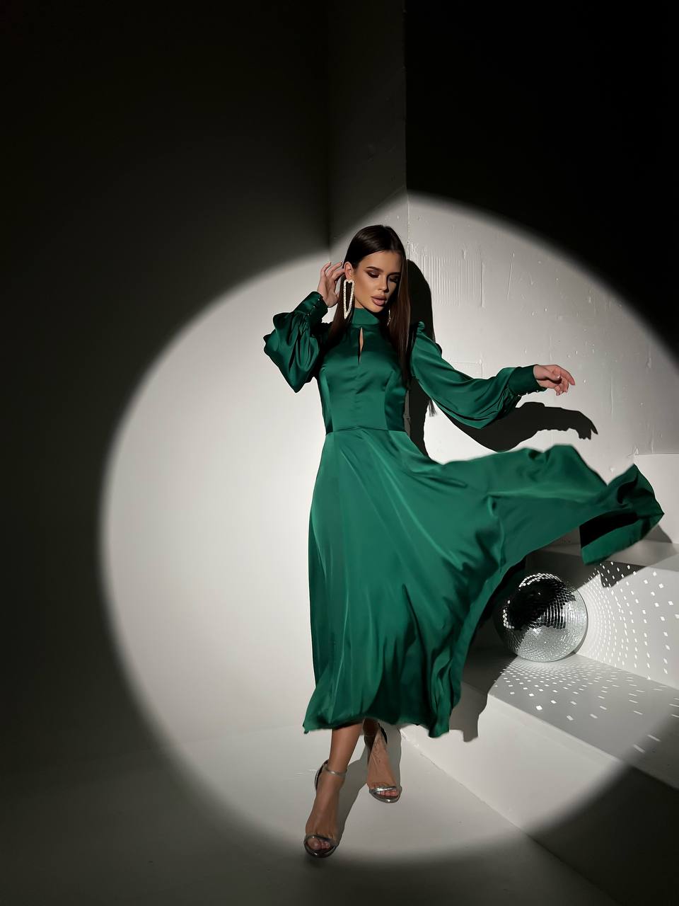Woman in a green dress posing in a spotlight on a white background
