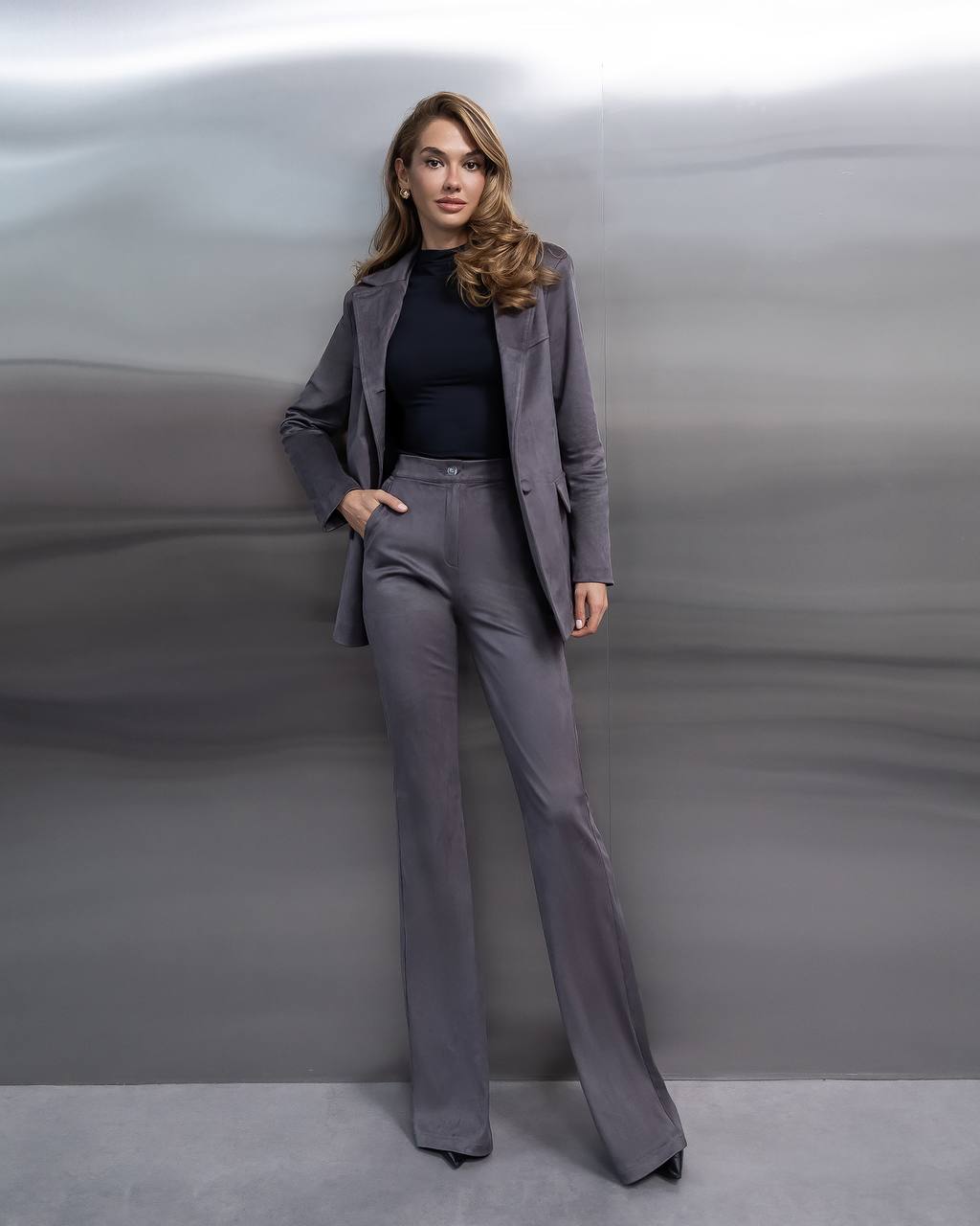 Woman wearing a gray suit against a gray background