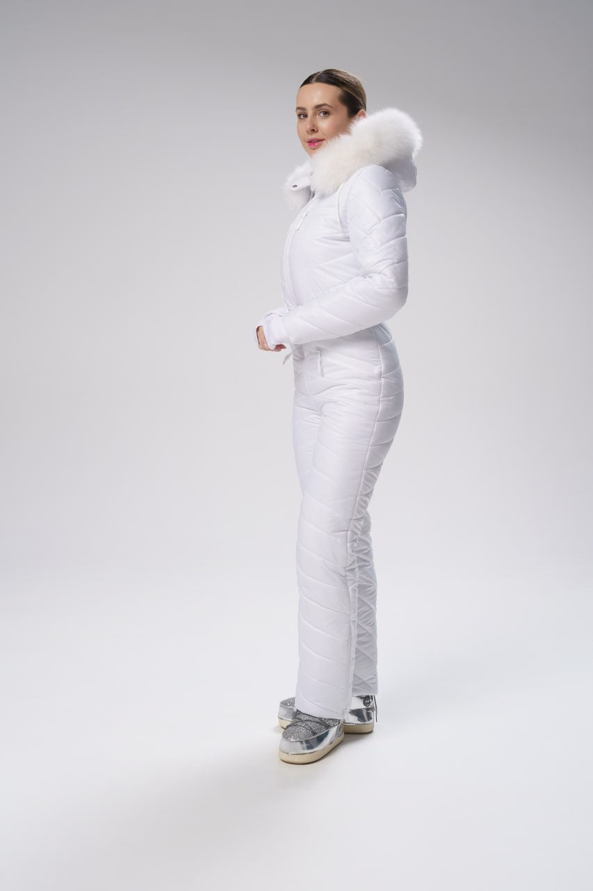 Person wearing a white puffer suit with fur trim on a gray background