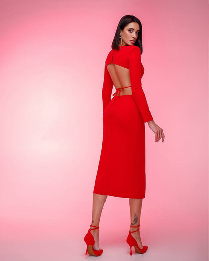 Woman wearing a red dress with cut-out design on a pink background