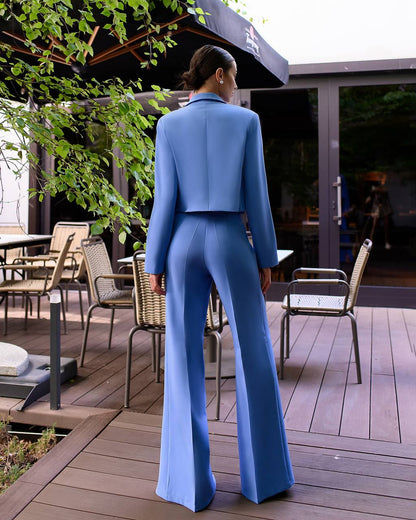 Person wearing a blue suit standing on a wooden deck with outdoor furniture.